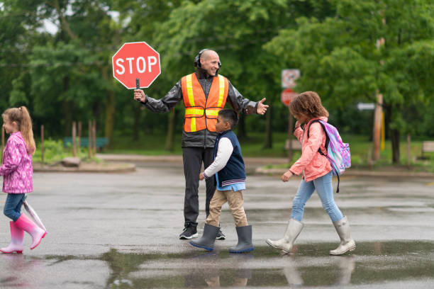 A crossing guard helping kids crosos the road, holding a stop sign